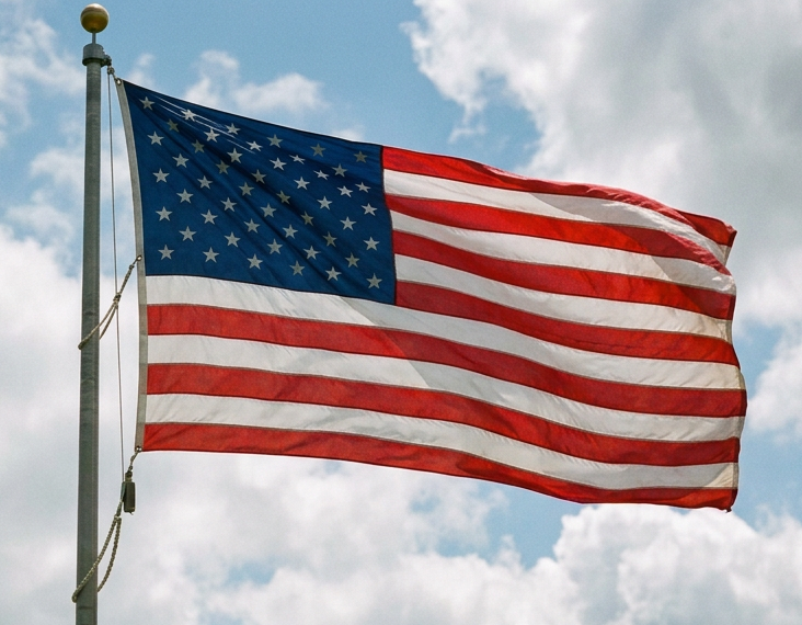 American flag waving on a flagpole above a grassy hill